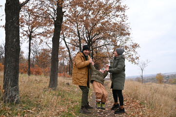 A mother, father, and son take a nature walk in a national park, warmly dressed, in the fall or winter without snow. Warm clothing for a hike for the whole family. Types of winter recreation