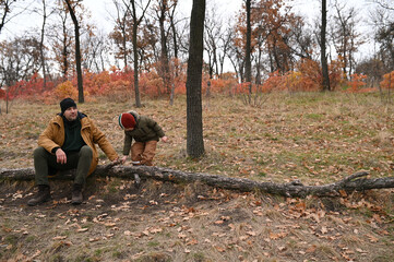A father and his preschooler son walk through the forest in the snowless winter or late fall. A solo parent and child, father and son. Outdoor play, active recreation, excursion to a national park, hi