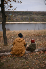 A father and son eat outdoors and drink tea from a thermos. An outdoor picnic in winter without snow or autumn