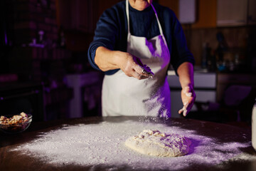 Person sprinkling flour on dough for baking