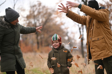 A mother, father, and son take a nature walk in a national park, warmly dressed, in the fall or winter without snow. Warm clothing for a hike for the whole family. Types of winter recreation
