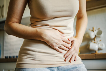 Woman suffering from stomach pain holding abdomen