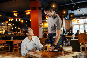 Waiter serving drink to customer in restaurant