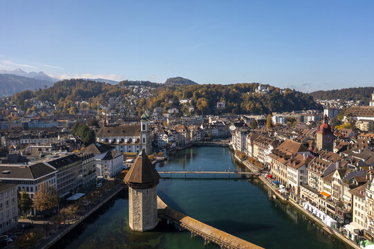 Aerial view of the Reuss River reflecting the old town's colorful buildings and the iconic Chapel Bridge, with the Water Tower standing tall, Lucerne, Lucerne, Switzerland.