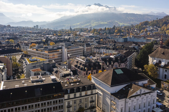 Aerial view of rooftops contrasting against the backdrop of distant mountains and a sky brushed with clouds, Lucerne, Lucerne, Switzerland.