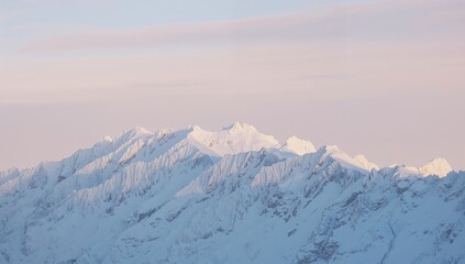 Naklejka premium Framing snowy mountain range showing warm-lit peaks at high elevation, rocky faces, pastel sky