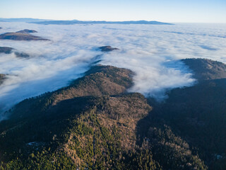 Aerial view of mountain peaks piercing through a sea of clouds, their slopes painted in contrasting shades of light and shadow, Ziare, Banska Bystrica Region, Slovakia.