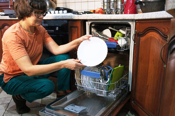 Woman taking a clean plate from the dishwasher