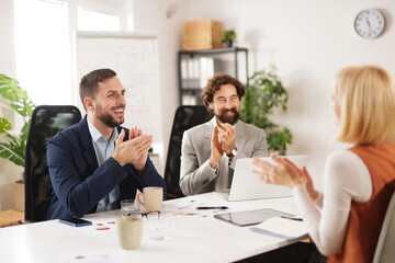 Team members gather in a bright office to collaborate and share ideas. They express enthusiasm and support for one another's contributions to the discussion.