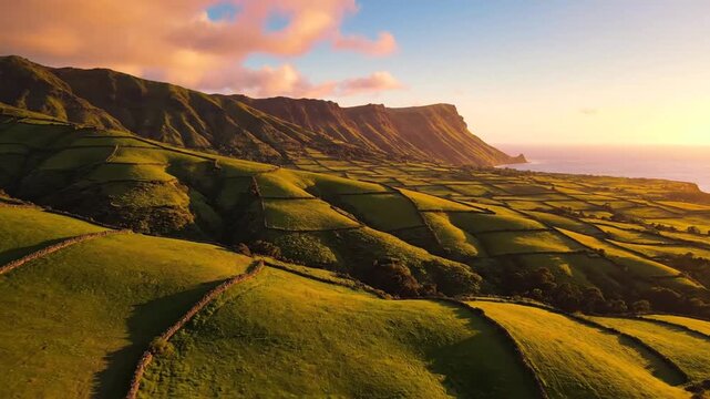 Golden-hour cliffs flank emerald terraced fields rolling toward a sea under warm pastel soft clouds