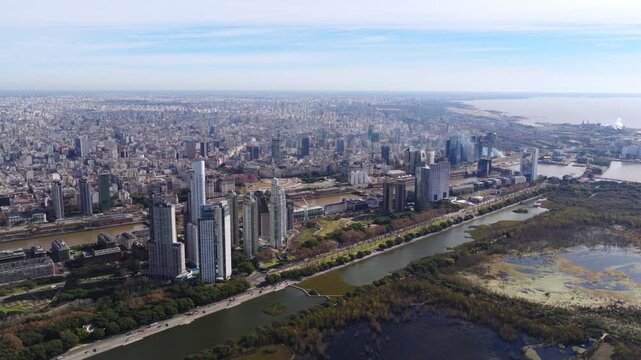Buenos Aires city skyline, featuring the skyscrapers of Puerto Madero and Catalinas Norte, adjacent to the green space of the ecological reserve wide aerial view.