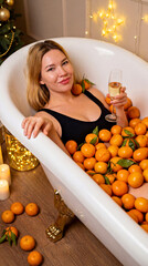 Woman Relaxing in Bathtub Filled with Oranges Holding Champagne