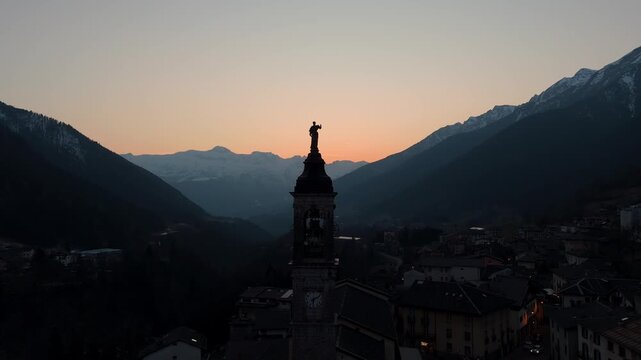 Aerial drone view over the church dome of Schilpario village in Val di Scalve, Italy, during a vibrant alpine sunset in the alpi orobie travel destination
