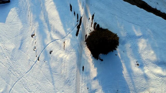 Aerial top-down drone view of snow-covered mountains in Val di Scalve, Italian Dolomites, and Alpi Orobie, with a small trekking path visible in the snow below