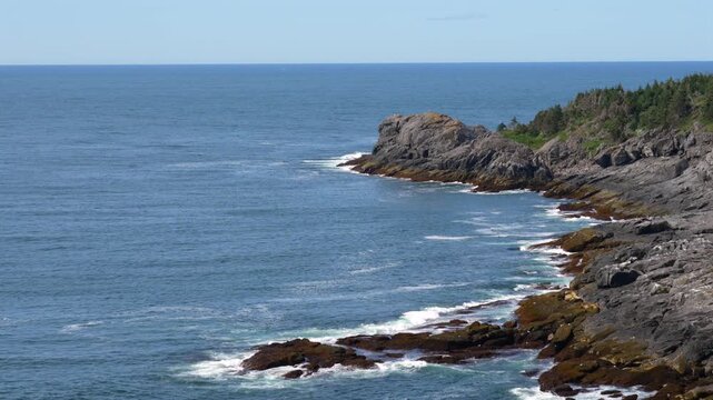 Waves from the ocean rolling in towards the rocky shoreline on the Maine coast.