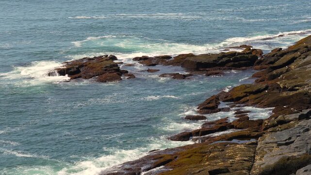 Waves from the ocean rolling in towards the rocky shoreline on the Maine coast.