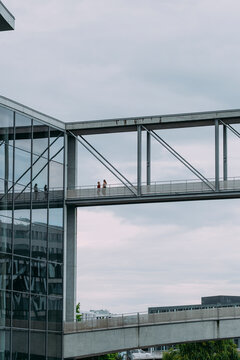 Modern urban architecture with pedestrians on glass bridge, city connection space highlighting people movement and contemporary architectural design