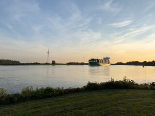 Containerschiff auf ruhigem Fluss bei Sonnenuntergang