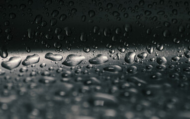 Water droplets on a dark metal surface.