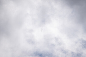 Fototapeta premium Silhouettes of twin jet aircraft emerging through heavy clouds during an overcast aerial maneuver.