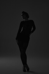 Elegant woman in black dress posing in dramatic low key lighting and shadow