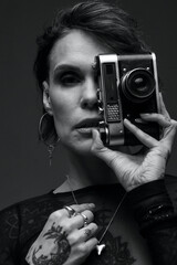 Woman with vintage camera and tattoos, black and white portrait