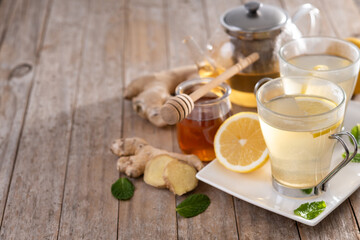 Ginger tea with honey and lemon in a cup on wooden table. Copy space