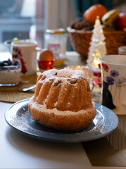 A plate Klougl with flowers, with Christmas holidays decoration atmosphere and festive ambiance. It's a cake traditionally baked in a distinctive ring pan.