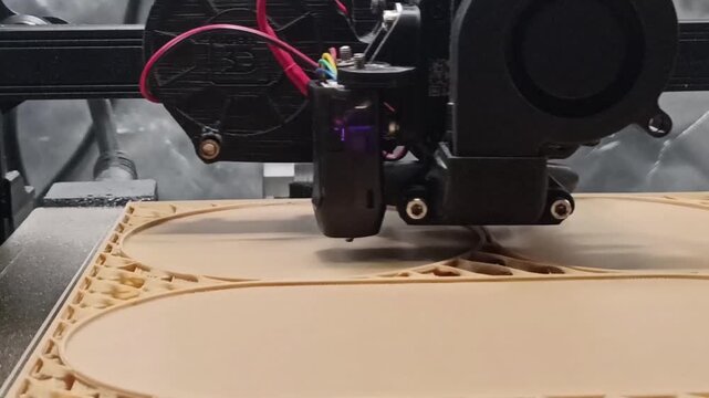 Detailed close-up shot of a Fused Deposition Modeling (FDM) 3D printer nozzle extruding light brown filament, building a complex container layer by layer.