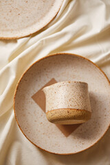Ceramic plates and a gravy boat on a white textile background. Handmade ceramics.