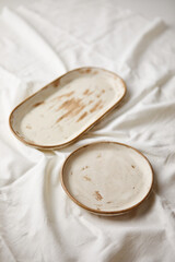 Ceramic plates on white textile background. Handmade ceramics.