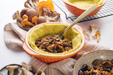 Quiche dough in a baking dish filled with mushroom filling of fried chanterelles, oyster mushrooms and champignons