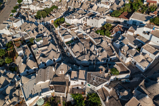 Aerial view of iconic Trulli houses with their conical roofs create a captivating mosaic of white and grey in the Apulian sun, Alberobello, Apulia, Italy.