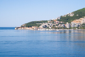 Mediterranean Tranquil Blue Sea Bay with Boats and Green Forest Peninsula under Clear Sky &ndash; Peaceful Coastal Landscape on Calm Summer Day