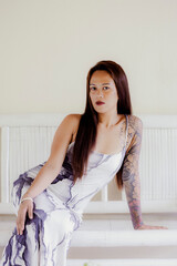 Woman in printed dress seated on indoor bench, leaning forward with graceful natural body language