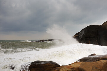 Under a cloudy sky, the waves crashed against the massive rocks, creating huge surges. (Scenic view of Hainan Stone Park, China)