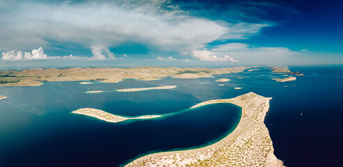 Aerial view of islands scattered like jewels across the deep blue sea, their rocky shores meeting the sky under a vast expanse of clouds, Kornati, Sibensko-kninska zupanija, Croatia.