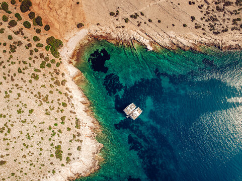 Aerial view of turquoise waters embracing the rugged coastline near Kornati with two boats drifting peacefully, Kornati, Sibensko-kninska zupanija, Croatia.