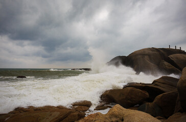 Under a cloudy sky, the waves crashed against the massive rocks, creating huge surges. (Scenic view of Hainan Stone Park, China)
