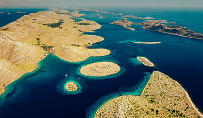 Aerial view of a scattering of islands, a blue expanse dotted with islets, bathed in sunlight, Kornati, Sibensko-kninska zupanija, Croatia.