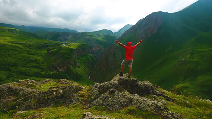 a backpacker in the mountains on top of a peak looks down at a gorge
