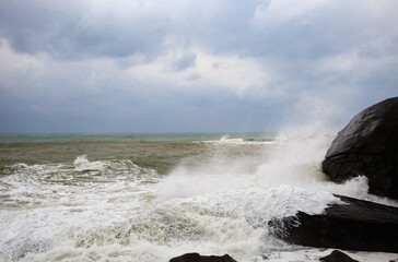 Under a cloudy sky, the waves crashed against the massive rocks, creating huge surges. (Scenic view of Hainan Stone Park, China)