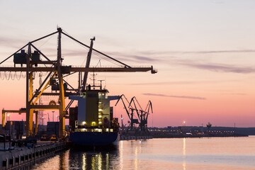Obraz premium Klaipeda Port at Sunset with cargo ships and industrial cranes, Lithuania