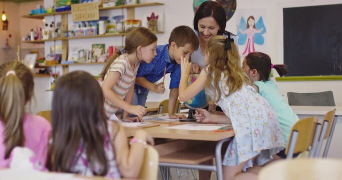 Female teacher showing a terrarium plant in a glass jar to a group of curious elementary students during a science lesson in a classroom, fostering interactive learning and discovery