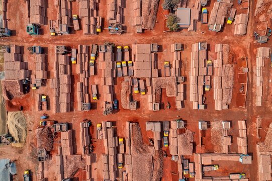 Aerial view of earthy red brick arrangements contrasting with touches of yellow and blue, creating a textured landscape, Aminbazar, Dhaka Division, Bangladesh.