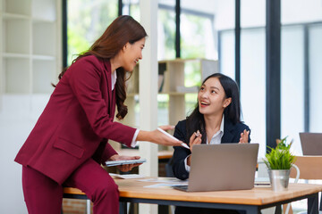 Asian businesswomen working together on business strategy, sharing ideas and expertise in a professional office environment