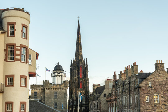 View of historic rooftops and a tolbooth Kirk church spire punctuate the skyline against a blue sky, creating a timeless urban tapestry, Edinburgh, Scotland, United Kingdom.