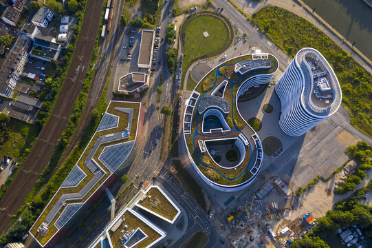 Aerial view of modern buildings with green roofs casting shadows next to railway tracks at Mediahafen, Dusseldorf, North Rhine-Westphalia, Germany.