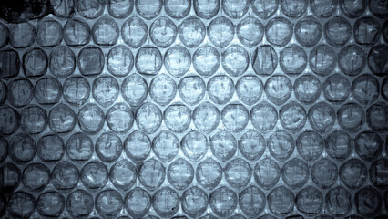Macro photograph of bubble wrap packaging material illuminated from below, revealing fine dust particles and organic imperfections. Soft blue-gray tones create a calm, evening-like atmosphere with sub