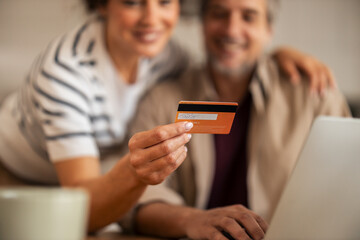 Happy Couple Using Credit Card for Online Purchase on Laptop in Cozy Home Setting